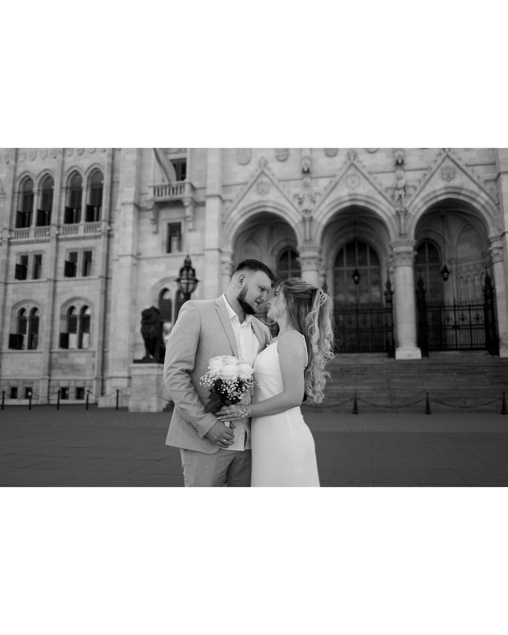 Newlyweds forehead to forehead in front of the Hungarian Parliament — black-and-white love story in Budapest