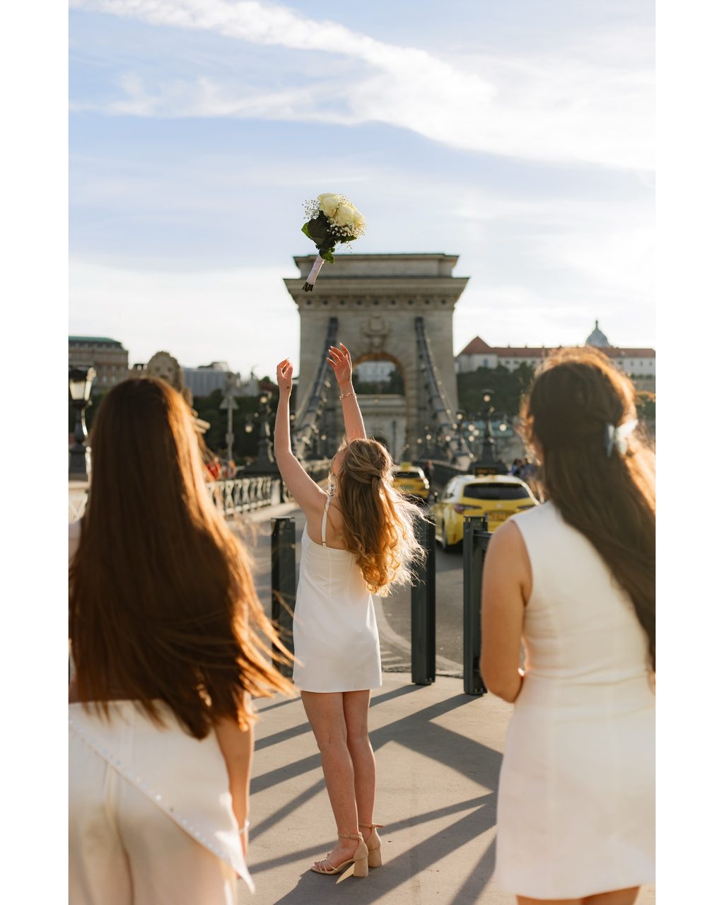 Bride tossing her bouquet on the Szechenyi Chain Bridge at golden hour — Budapest wedding